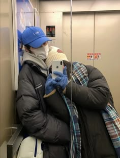 a man wearing a blue hat and scarf is taking a selfie in the subway