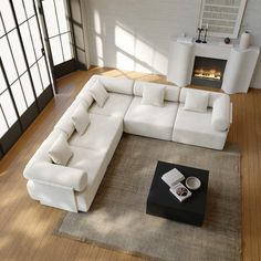 a large white sectional sofa sitting on top of a wooden floor next to a fire place