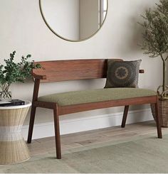 a wooden bench sitting in front of a mirror next to a plant and potted tree