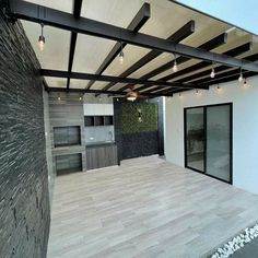 an outdoor kitchen and dining area with wood flooring, white walls and ceiling lights