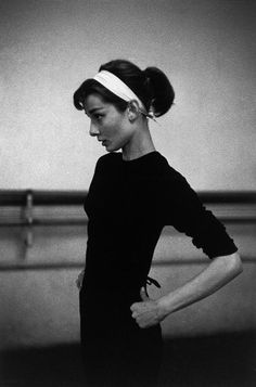 a black and white photo of a woman with her hands on her hips wearing a headband