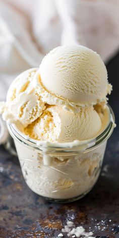 two scoops of vanilla ice cream in a glass bowl on a table with salt scattered around