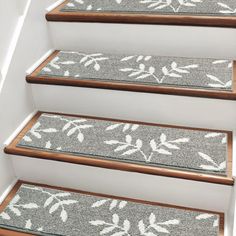 the carpeted stairs are decorated with white flowers and leaves on grey rugs, along with wooden handrails