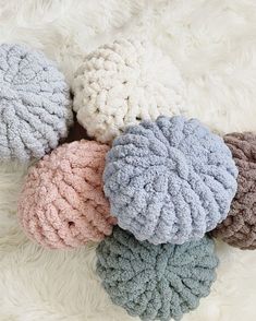 four different colors of knitted beanie hats on a white furnishing surface