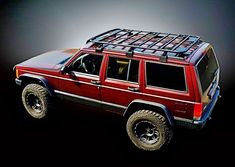 a red jeep with luggage strapped to it's roof rack and four wheel drive