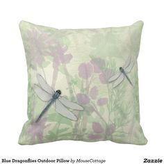 a pillow with two dragonflies sitting on it's back and flowers in the background