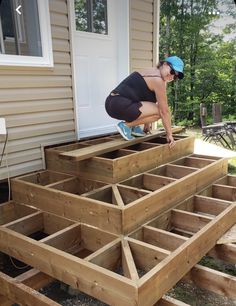 a woman kneeling down on top of some wooden steps in front of a house,