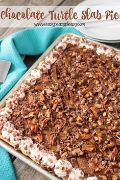 a chocolate turtle slab pie with whipped cream and pecans in the middle on a wooden table