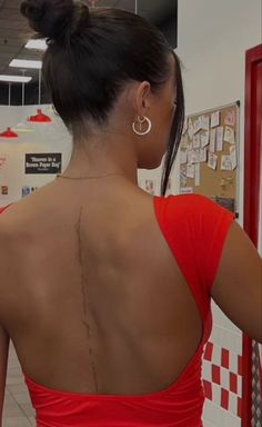 the back of a woman's body in a red dress with tattoos on it