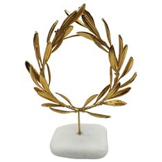 Gold-plated 24Ct Olive Oval Wreath in real White Greek Marble Base 20cm The Golden Olive Wreath is a real wreath of olive branches, a Greco-Roman style wreath on a white marble base. It is a metallized wreath of olive branches. It is plated with copper and gold plated with 24Ct. An amazing, Greek crown, just like the one worn by Olympians and many distinguished heads in antiquity. This gorgeous, elegant wreath is all gold plated with a few leaves, gold plated. Harvested from a typical Greek oliv Real Wreath, Olive Crown, Greek Crown, Oval Wreath, Olive Branch Wreath, Golden Wreath, Elegant Wreath, Olive Plant, Olive Wreath