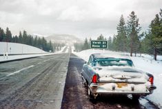 an old car is parked on the side of the road covered in snow and ice