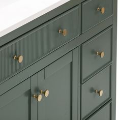 a green bathroom vanity with brass handles and knobs