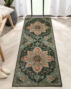 a large green rug with an ornate design on the floor in front of a window