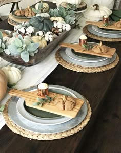 the table is set for thanksgiving dinner with pumpkins, gourds and other decorations