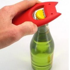 a hand holding a bottle opener over a green bottle with a yellow object in it