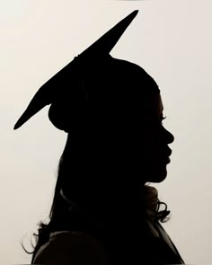 the silhouette of a woman wearing a graduation cap with a long pointed peak on her head