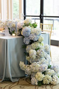 the table is set with blue and white hydrangeas, candles and napkins