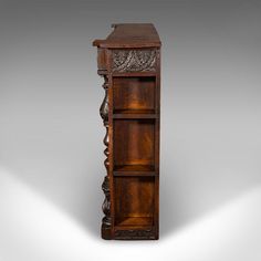 an old wooden bookcase with carvings on the top and bottom shelf is shown against a gray background