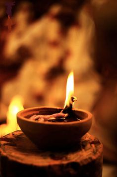 a lit candle sitting on top of a piece of wood in front of some fire