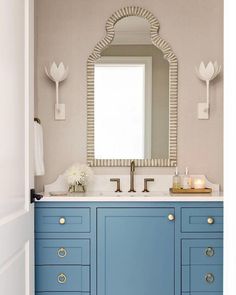 a bathroom with blue cabinets and a large mirror above the sink in front of it