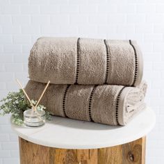 two towels stacked on top of each other next to a vase with flowers in it