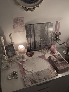 a table with candles, pictures and other items on it in front of a mirror