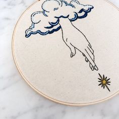 an embroidery project with a hand holding a star in the sky on a marble surface