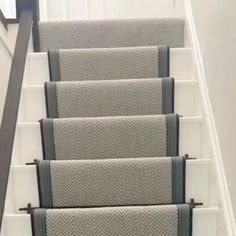 the carpeted stairs are lined with gray and white rugs