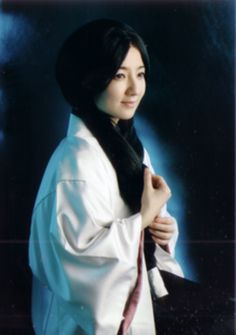 a woman wearing a white kimono posing for a photo with her hands on her hips