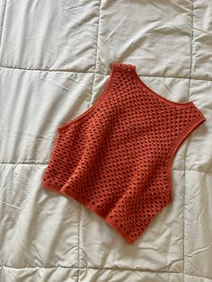 an orange crocheted top laying on a bed