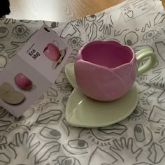 a pink cup and saucer sitting on top of a table next to a box