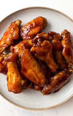 a white plate topped with chicken wings covered in sauce