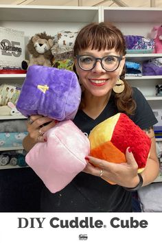 a woman holding two stuffed animals in front of a bookcase with the title diy cuddle, cube