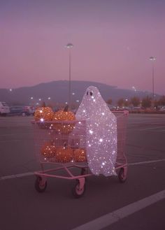 a shopping cart filled with oranges sitting on top of a parking lot at night