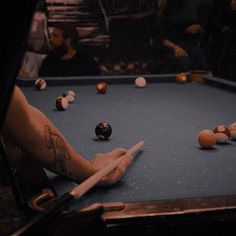 a pool table with several balls and sticks on it, in front of a group of people