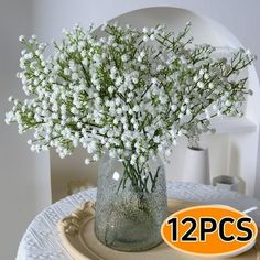 a glass vase filled with white flowers on top of a table