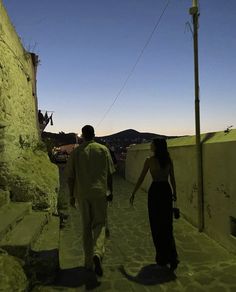 two people walking down a stone path in the evening