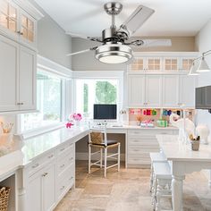 a kitchen with white cabinets and a ceiling fan in the middle of it's center island