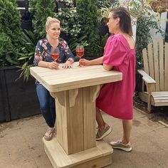 two women sitting at a table with wine glasses