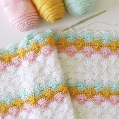 two crocheted afghans next to each other on a table with knitting needles