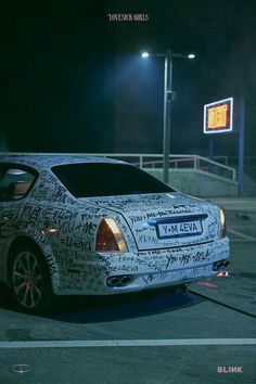 a white car parked in front of a gas station at night with writing all over it