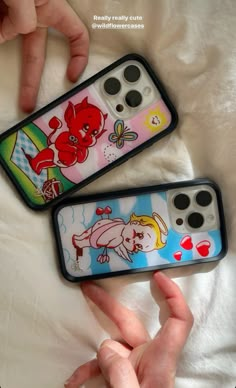 two cell phones with cartoon characters on them sitting on a white bed next to each other