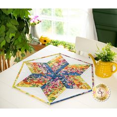 a table with a quilted star on it next to a potted plant