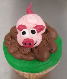 a cupcake with pink frosting and a pig face on top