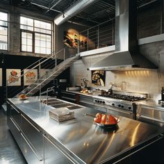 an industrial kitchen with stainless steel counter tops and stairs leading up to the second floor