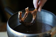 someone is dipping pretzels into chocolate in a saucepan