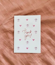 a thank you card with hearts and bows on it sitting on top of a bed