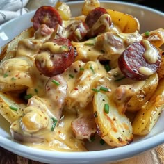 a white bowl filled with potatoes covered in cheese and sausages, on top of a wooden table