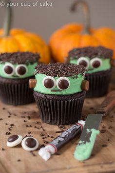 some cupcakes with green frosting and googly eyes are on a table