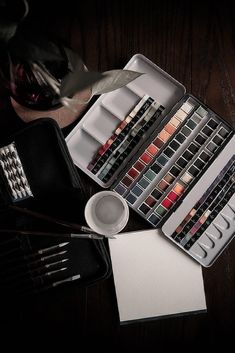 an assortment of watercolors and brushes on a table